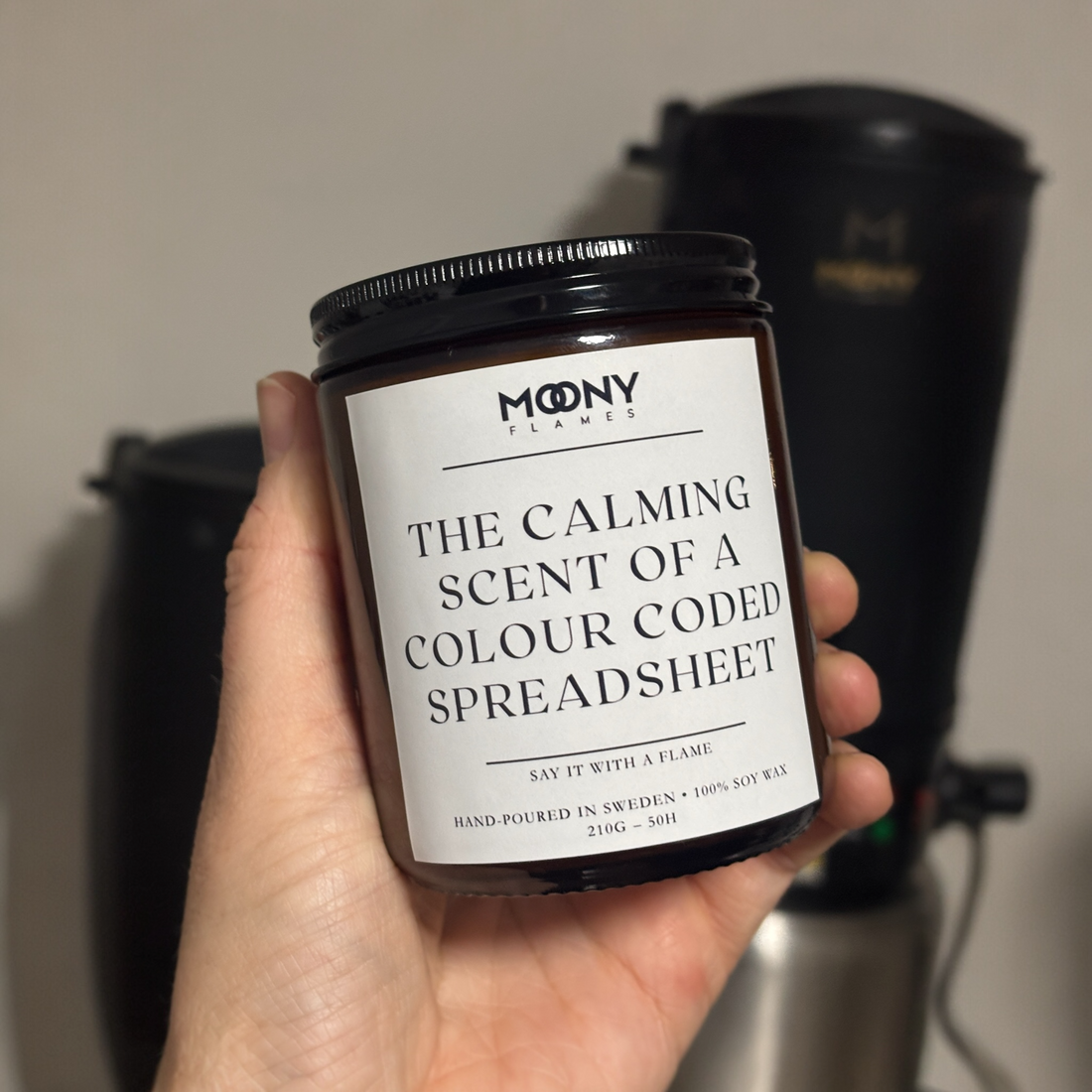 Personligt doftljus med budskap från moony flames som hålls i handen i ljusstudio.