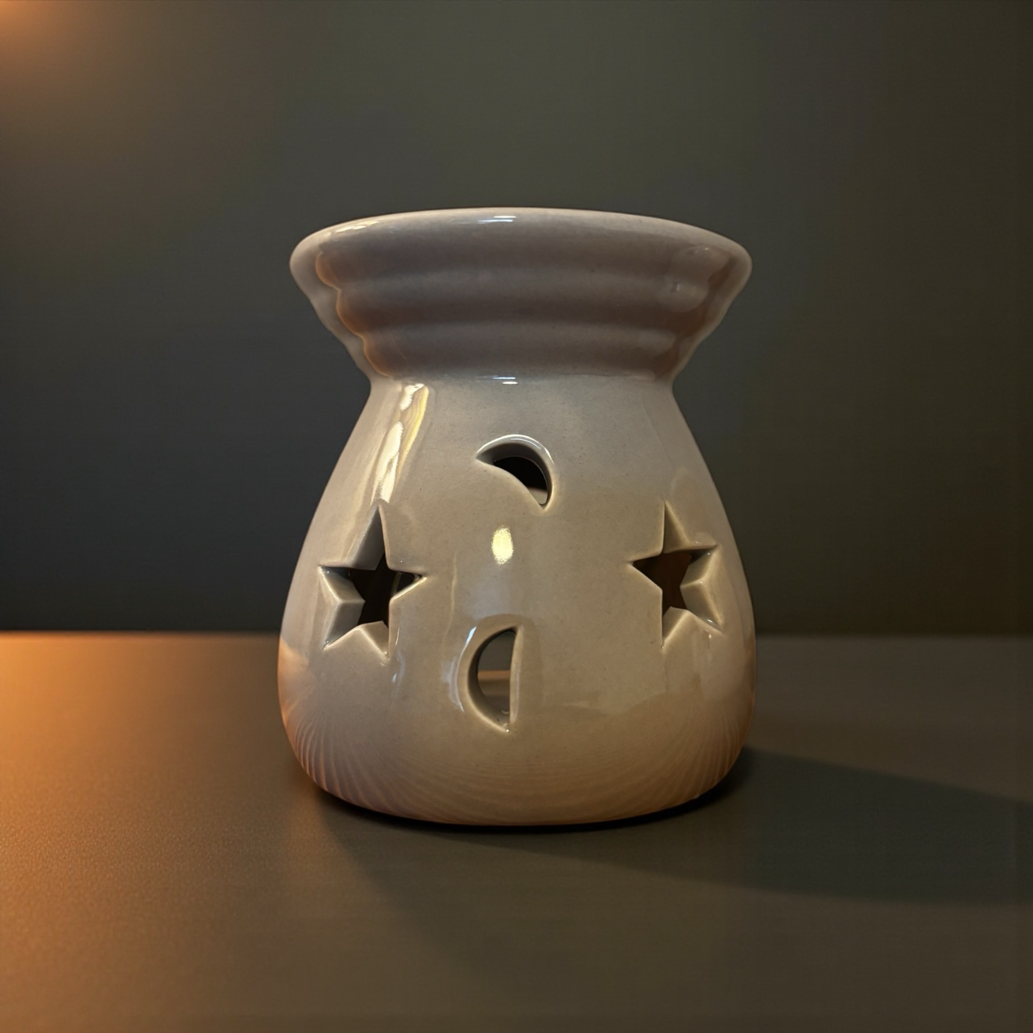 Moony Flames aromalampa i ljusgrå som har små sjärnor och månar och som står framför en mrk bakgrund.