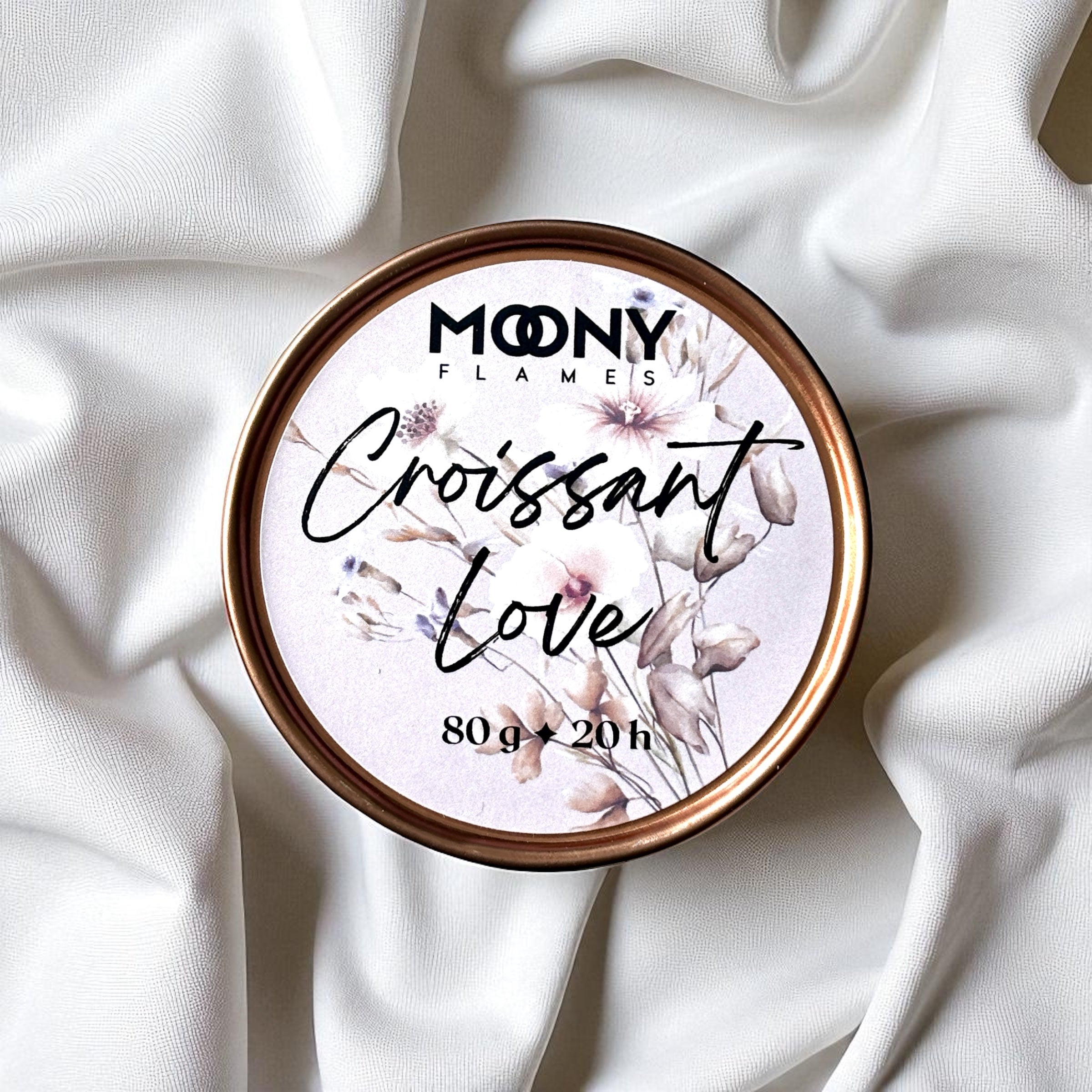 Doftljus Croissant Love i roseguld metallburk på en vit duk uppifrån. Reseljus - Moony Flames