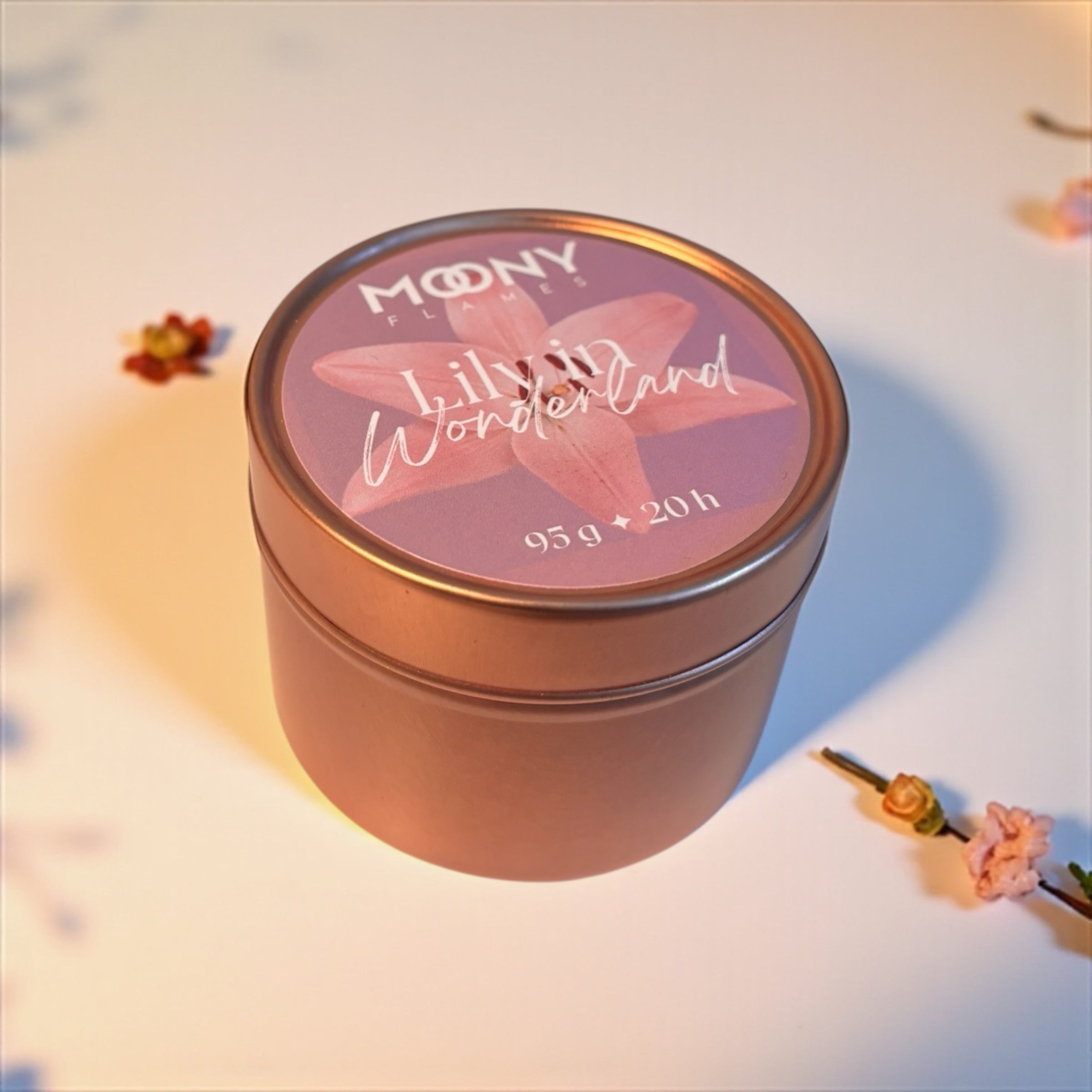 Doftljus Lily in Wonderland från Moony Flames i metallburk. Ljuset visas lite frå sidan och stor på en vit undergrund med små blommor.