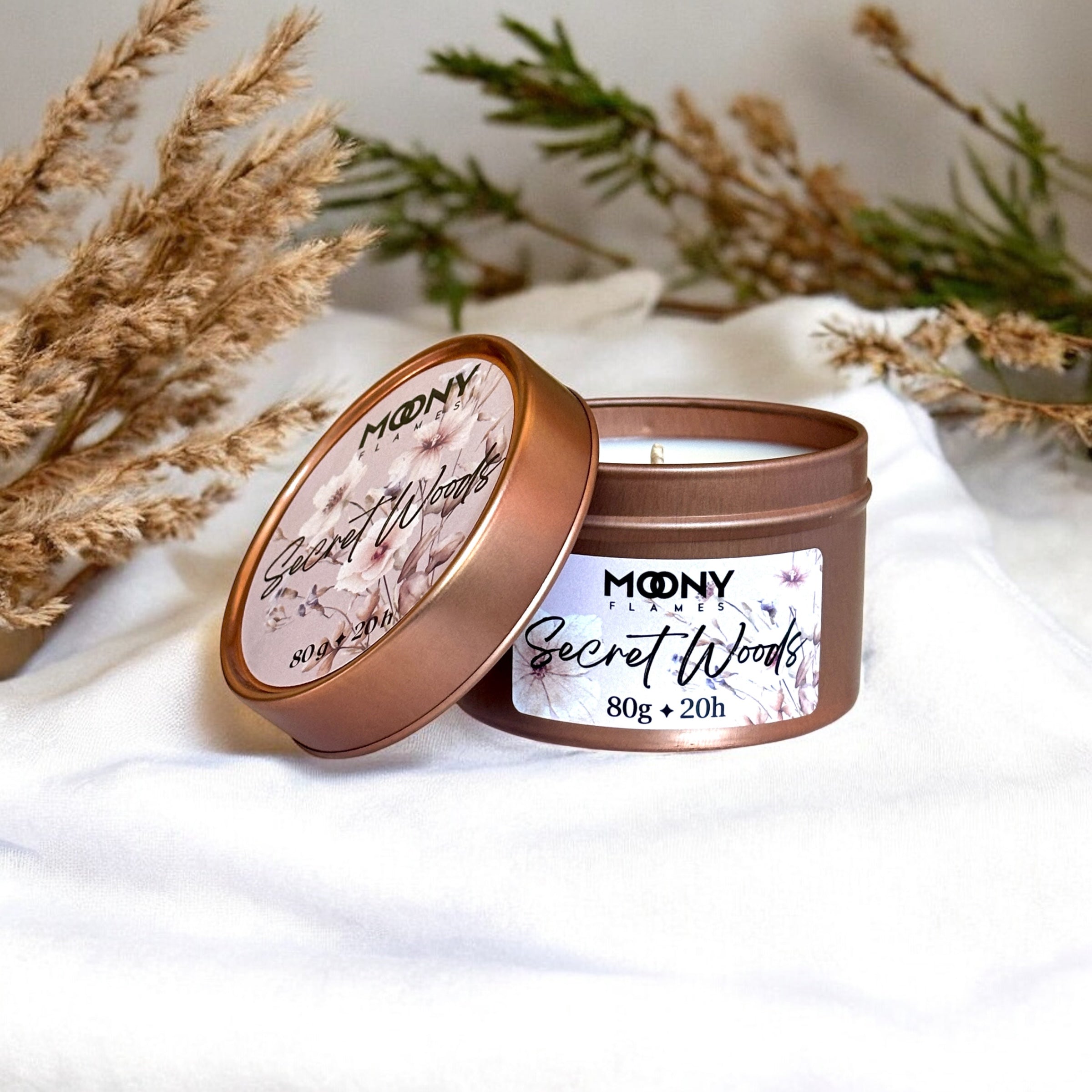 Doftljus Secret Woods i roseguld metallburk på en vit duk. Reseljus - Moony Flames