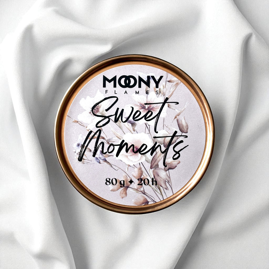Doftljus Sweet Moments i roséguld metallburk som ligger på en vit duk. Reseljus - Moony Flames