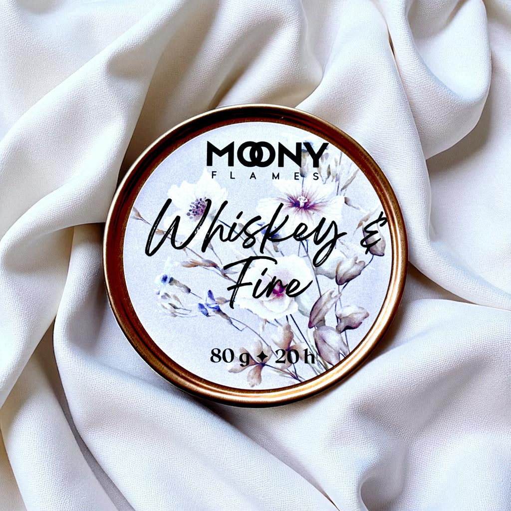 Doftljus Whiskey and Fire som reseljus i roséfärgad metallburk som står på en vit duk - Moony Flames.