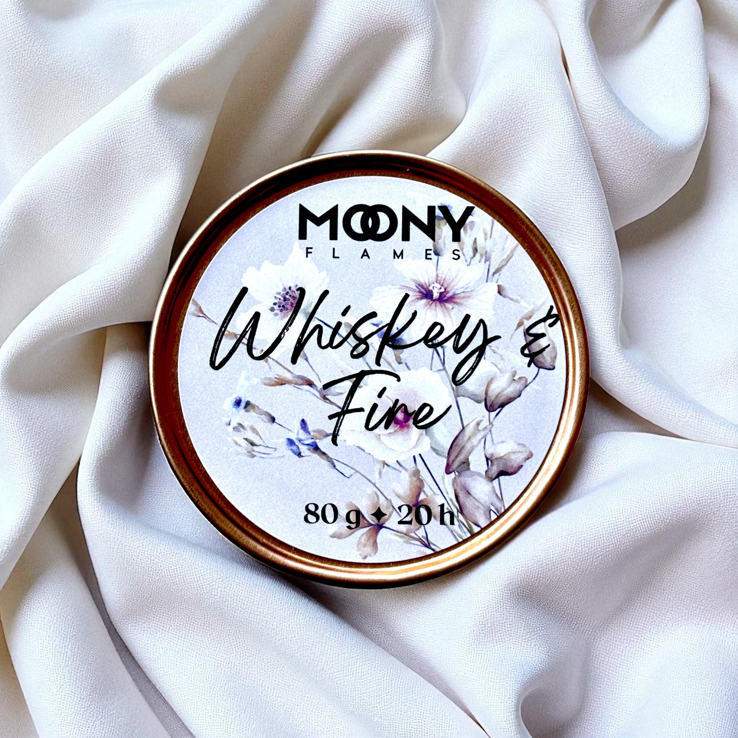 Doftljus Whiskey and Fire som reseljus i roséfärgad metallburk som står på en vit duk - Moony Flames.