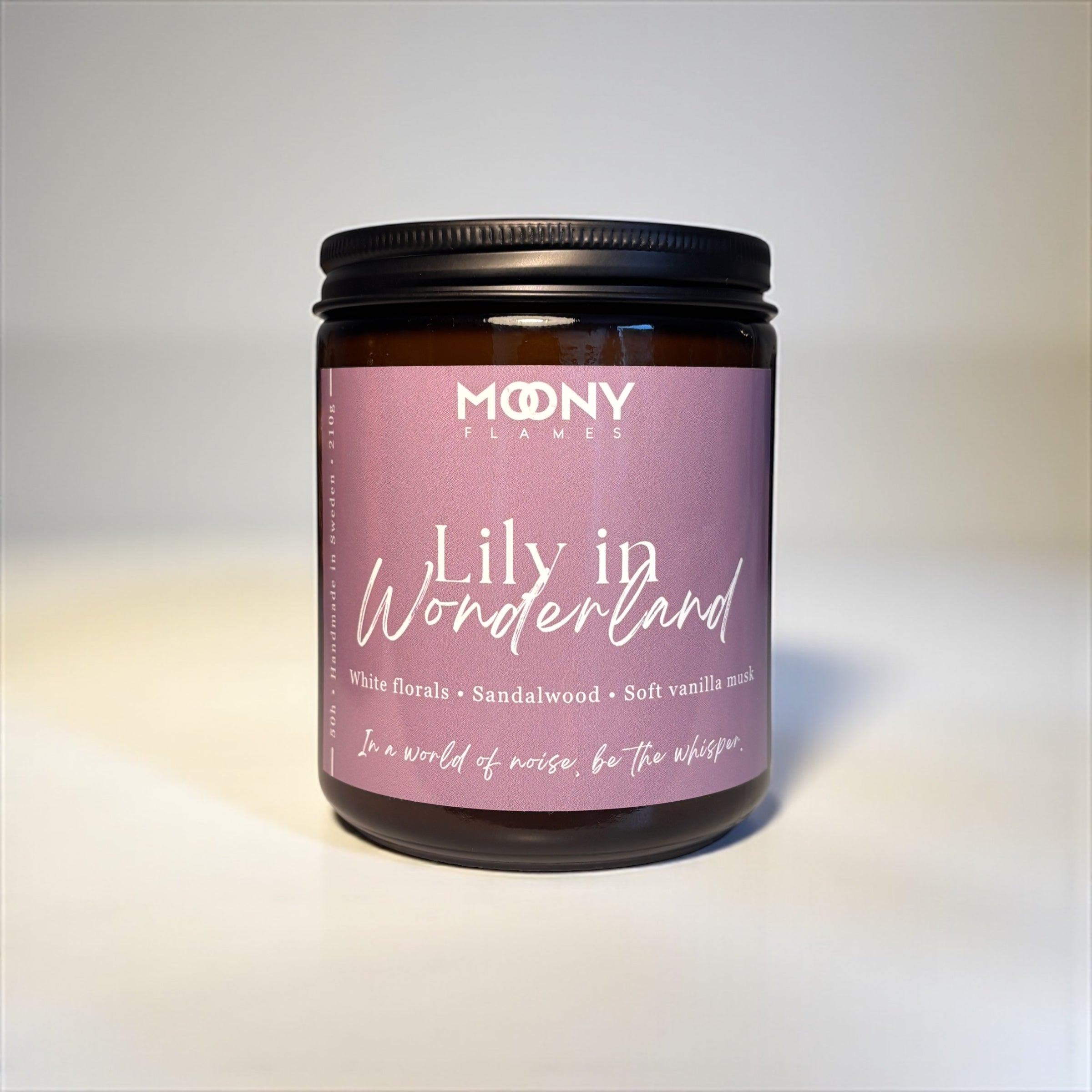 Doftljuset Lily in Wonderland i amber glasburk med svart skruvlock som visas professionellt fotograferat framför en vit bakgrund. 