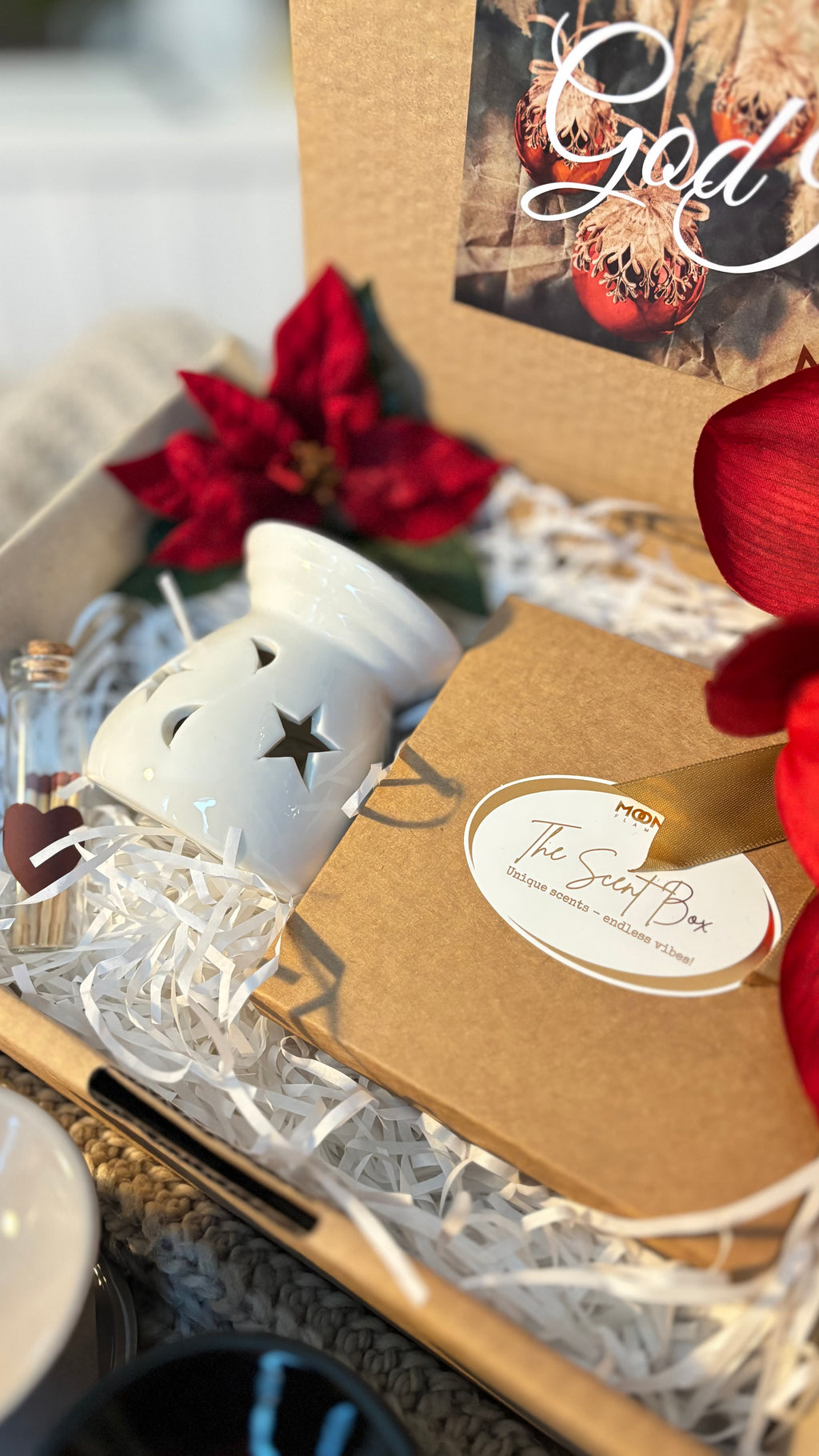 En öppen presentlåda som visar asken med doftpralinerna samt en vit aromalampa och en liten glasflaska med tändstickor.