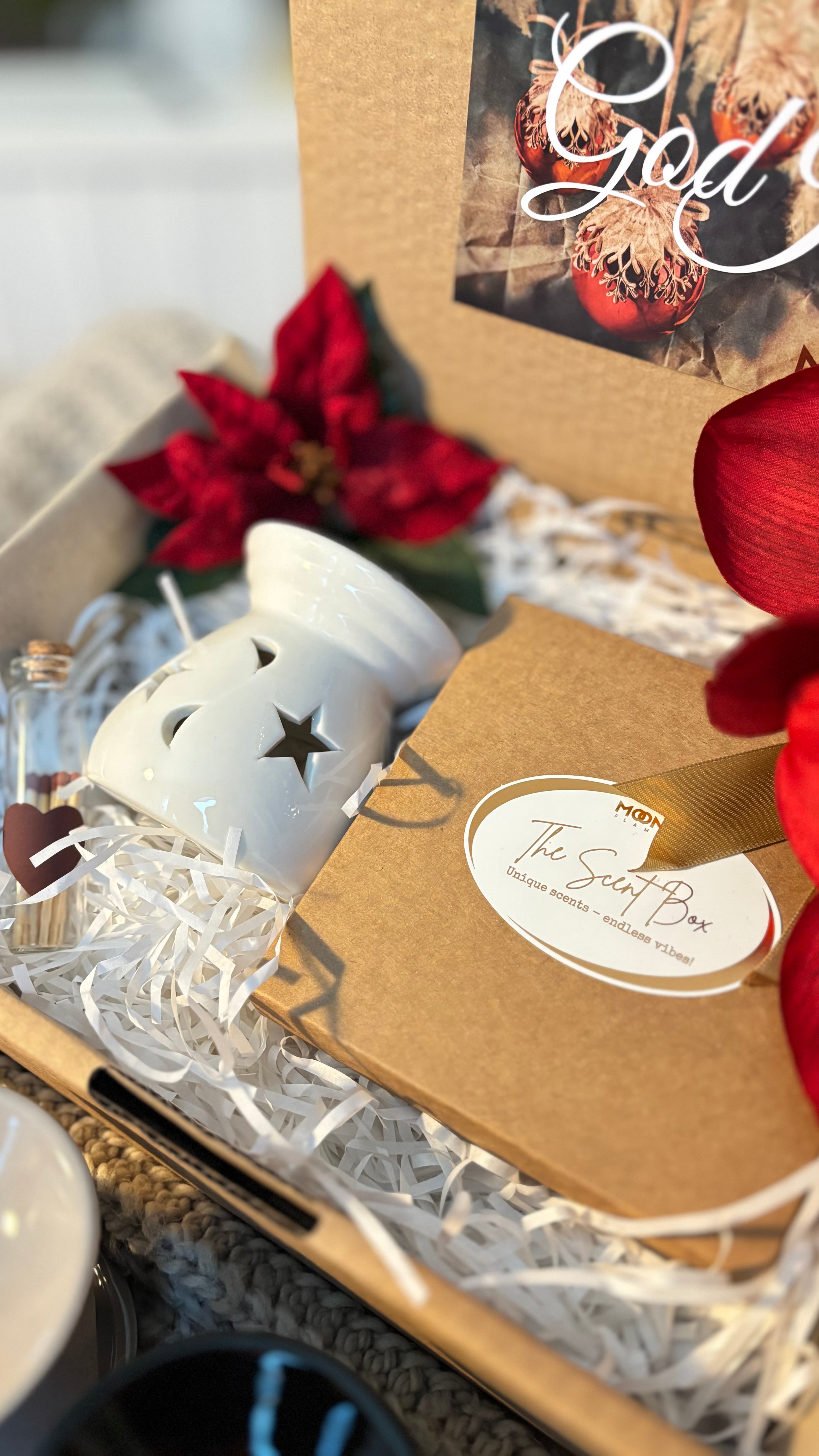 En öppen presentlåda som visar asken med doftpralinerna samt en vit aromalampa och en liten glasflaska med tändstickor.