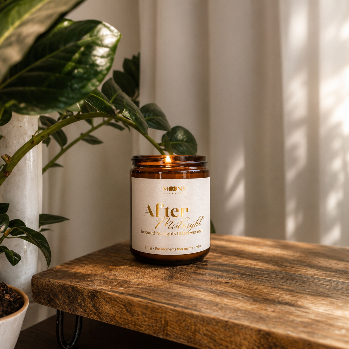 Handgjort After Midnight doftljus från Moony Flames i amberglas med guldfolierad etikett. Produktbild med grönska, varm belysning och naturliga material som framhäver doftnoter av körsbär, hallon, björnbär och vanilj. Tillverkat i Småland, Sverige.