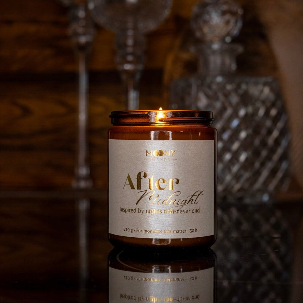 Handgjort doftljus “After Midnight” i amberglas på bord i elegant kvällsmiljö med varm låga