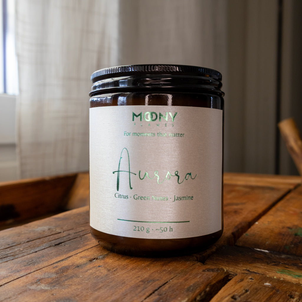 Aurora doftljus från Moony Flames, inspirerat av norrskenets färger och den friska känslan av naturen. Handgjort doftljus i sojavax med noter av citrus, gröna toner och jasmin, tillverkat i Småland, Sverige.