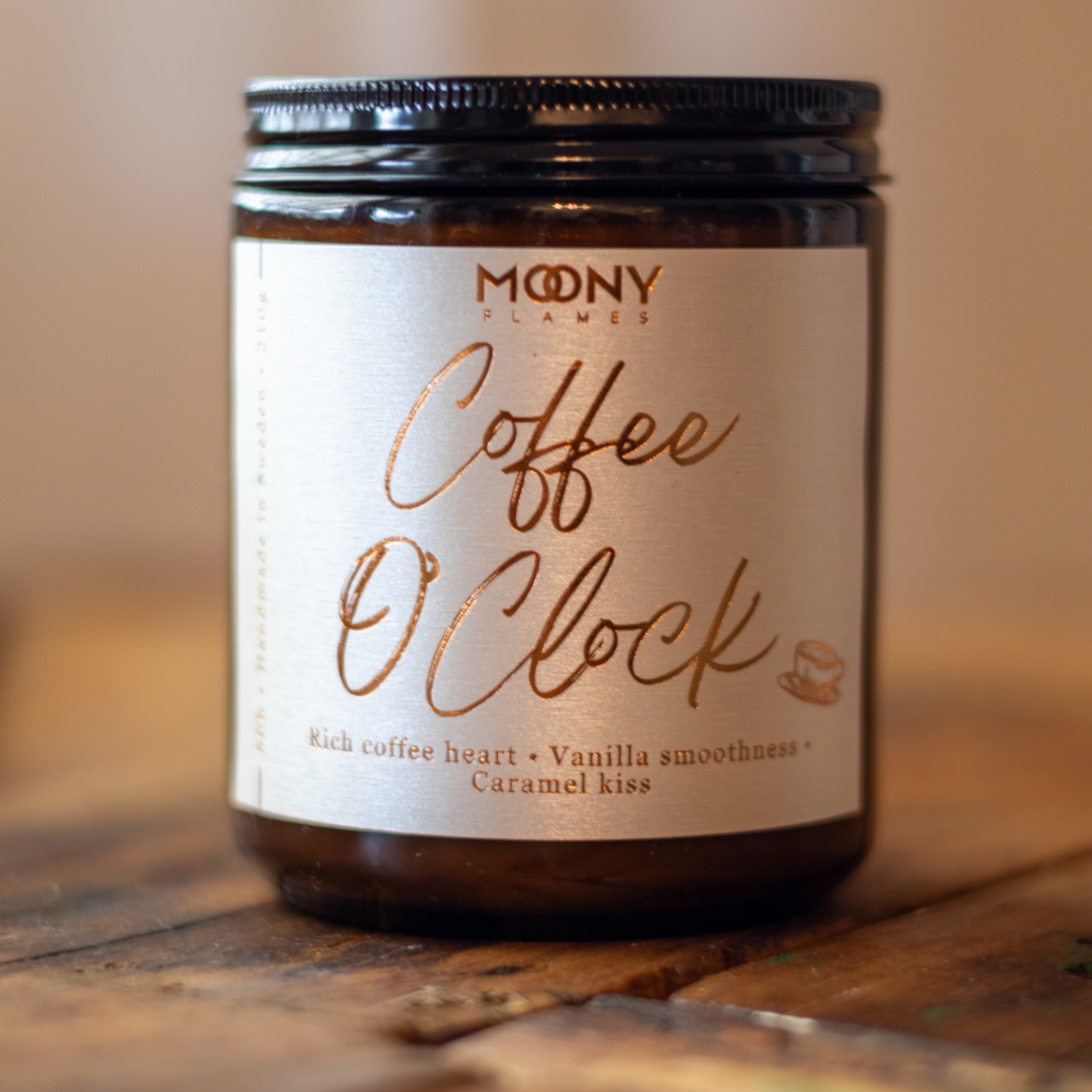 Coffee O'Clock doftljus från Moony Flames med doft av nybryggt kaffe, vanilj och karamell. Handgjort doftljus i amberglas tillverkat i Småland, Sverige av växtbaserat vax för en varm och mysig atmosfär i hemmet.