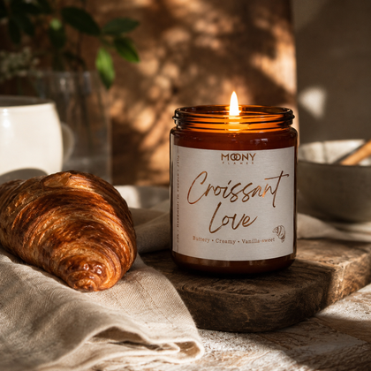 Tänt Croissant Love doftljus från Moony Flames som fångar känslan av en lugn helgfrukost med nybakade croissanter, mjukt morgonljus och ett hem fyllt av värme.