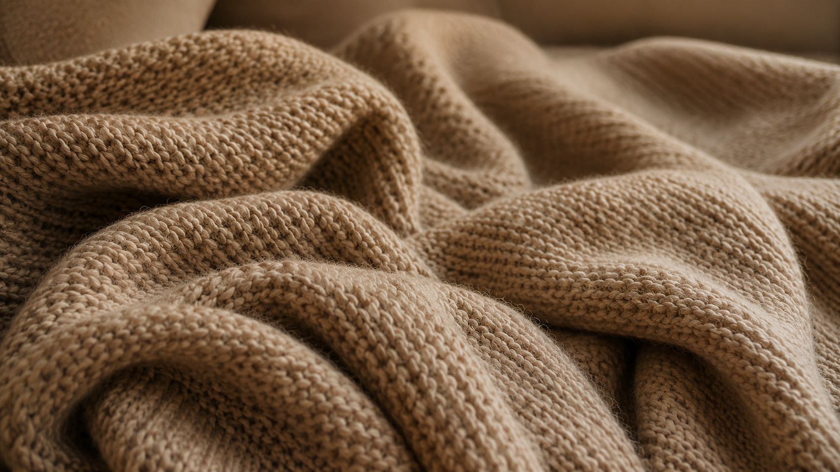 Mjuk beige stickad filt i varmt ljus som skapar en ombonad och mysig känsla för hösten.