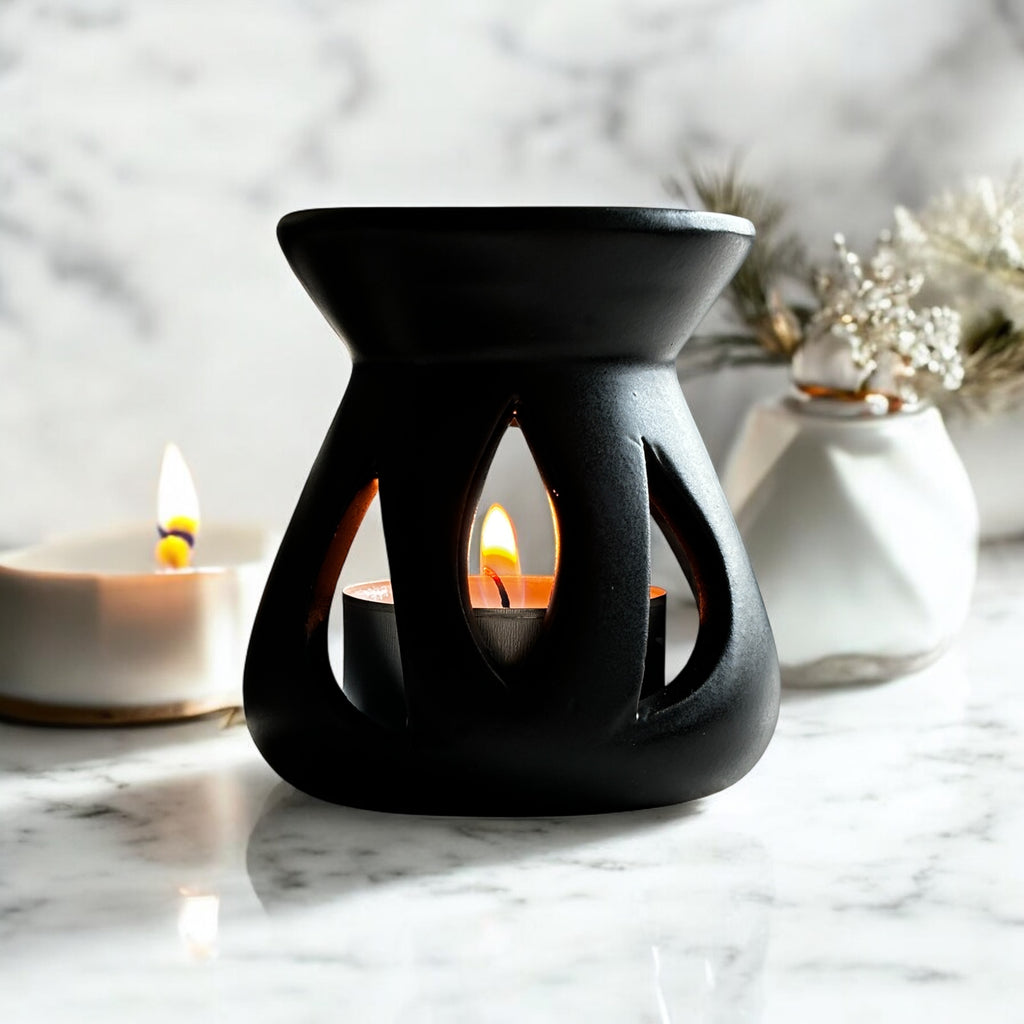 Black Lotus aromalampa i svart keramik – liten doftlampa för doftvax och eteriska oljor som sprider ett mjukt ljus och behaglig doft, som står på en marmorbänk i ett badrum.