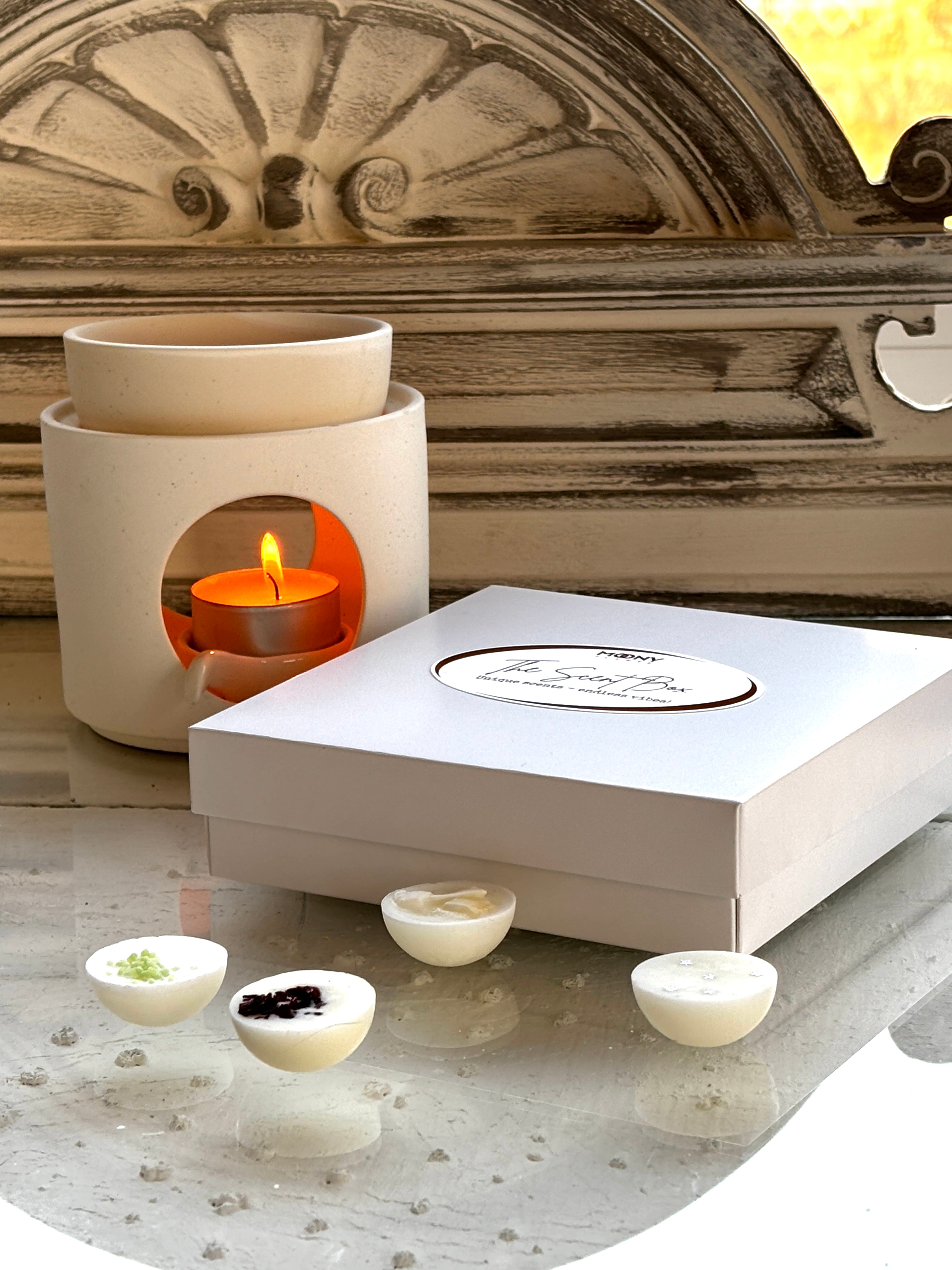 Handgjorda doftvaxer från The Scent Box, dekorerade med ekologiska blommor för en unik doftupplevelse, med aromalampa i bakgrund.