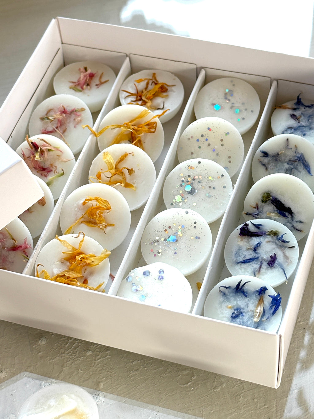 Handgjorda doftvaxer från The Scent Box, dekorerade med ekologiska blommor för en unik doftupplevelse, praliner i presentask.
