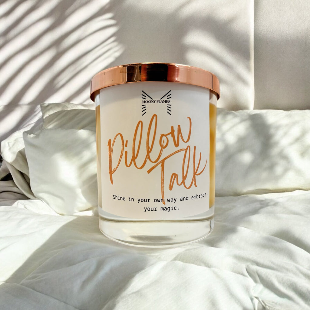 Pillow Talk handgjort doftljus, veganskt, svensktillverkat växtbaserat vax, marmorerat designljus, miljövänligt doftljus, unikt ljus från Moony Flames, i en säng med kuddar.