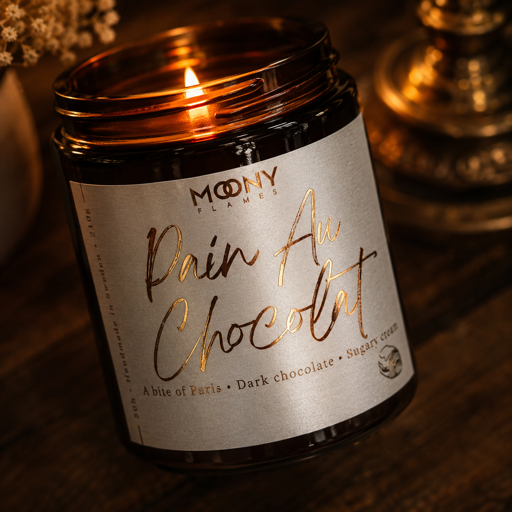 Tänt Pain Au Chocolat doftljus från Moony Flames som fyller hemmet med känslan av ett franskt bageri, nybakade chokladcroissanter och en lugn helgmorgon.