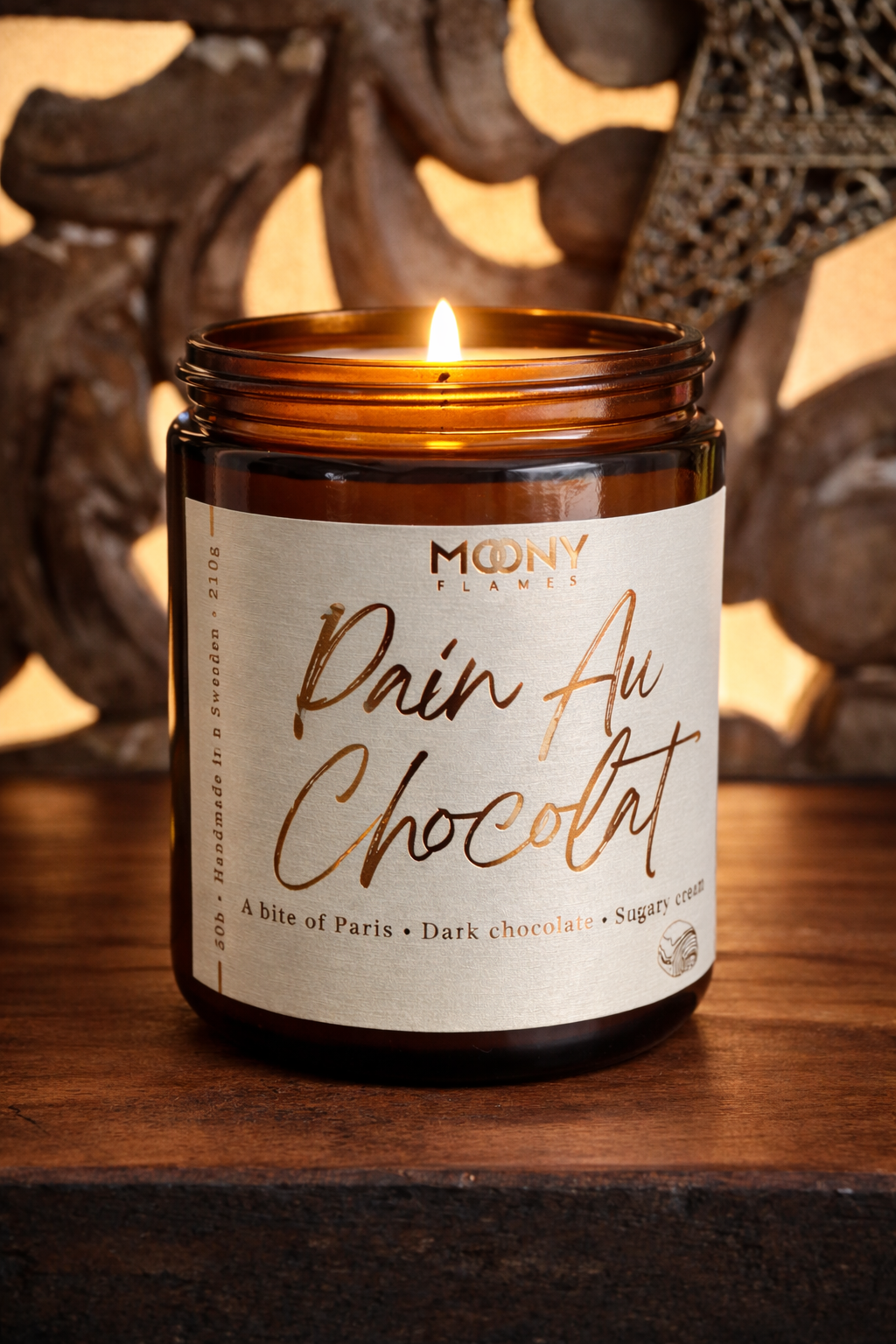 Brinnande Pain Au Chocolat doftljus från Moony Flames i amberglas, ett gourmand-doftljus med noter av mörk choklad och söt grädde, inspirerat av Paris.