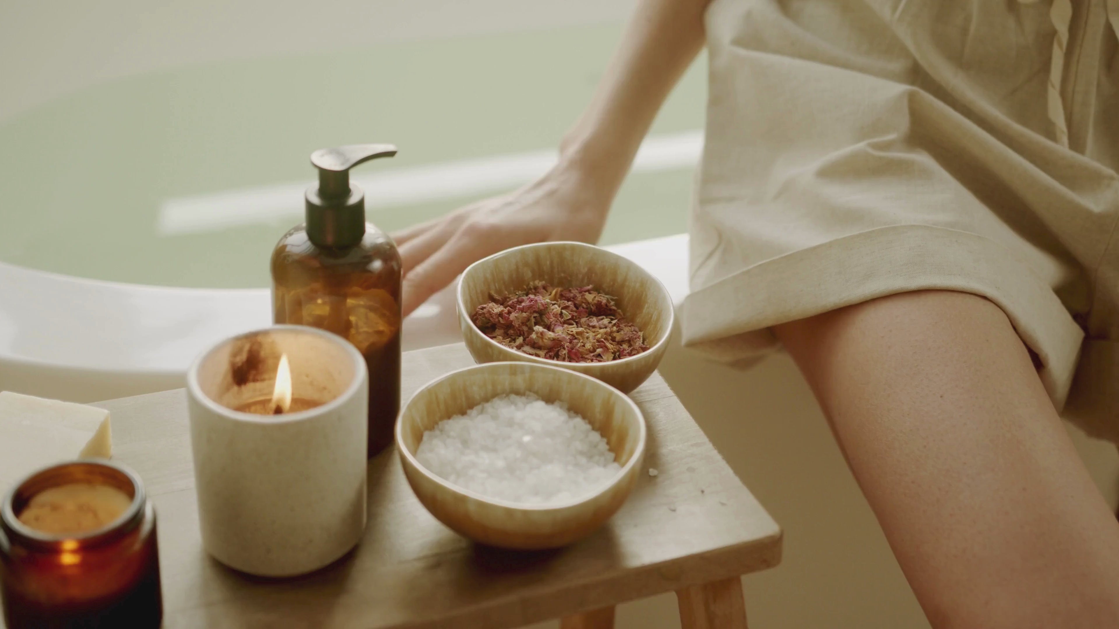 Kvinna förbereder ett bad med badsalt och tända doftljus – handgjort doftljus från Sverige för avslappning och mindfulness.