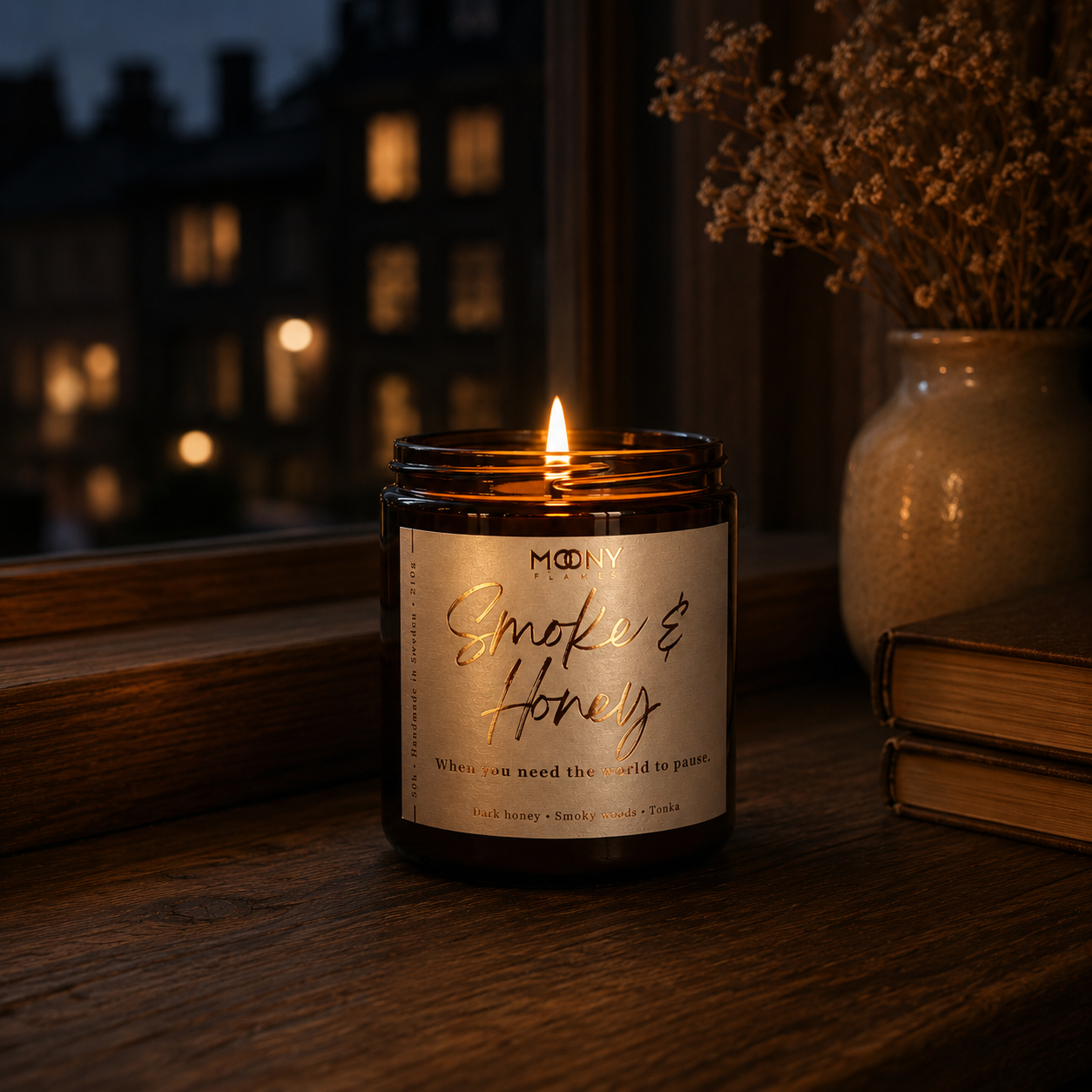 Handgjort doftljus Smoke & Honey från Moony Flames tänt i ett fönster en lugn kväll med varm belysning och utsikt över staden.