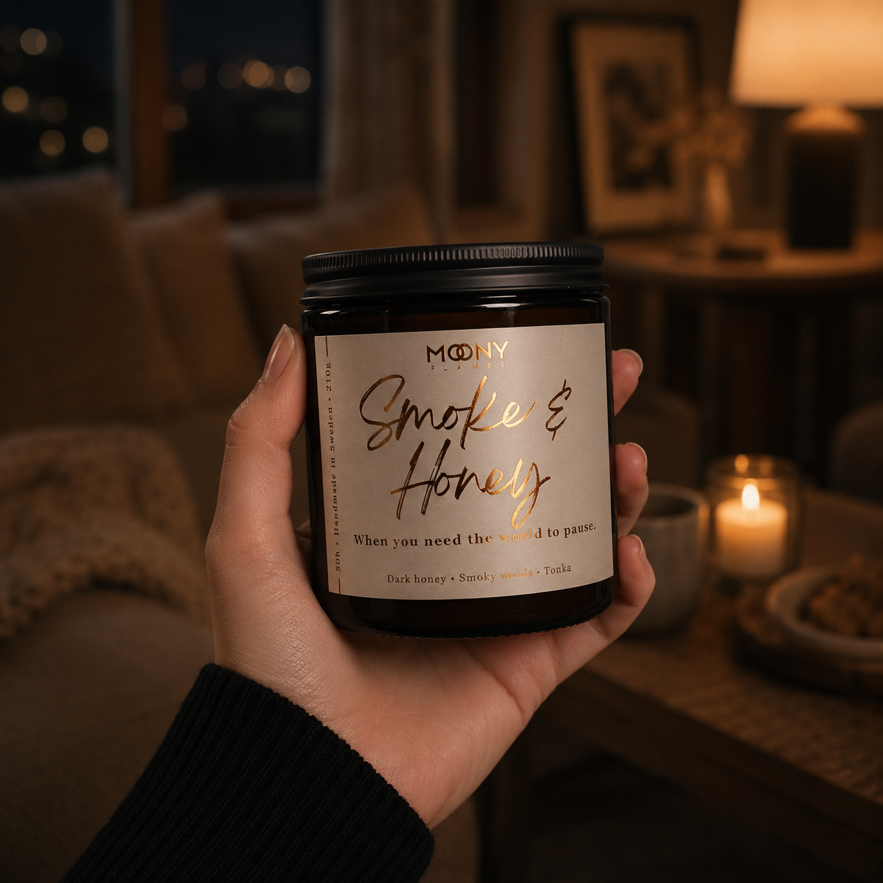 Smoke & Honey handgjort doftljus från Moony Flames i handen, skapat för lugna kvällar där doften av honung och rökiga tränoter gör hemmet varmt och ombonat.