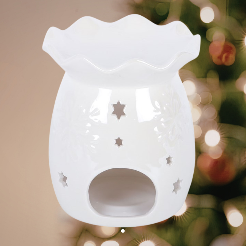 Snowflake doftlampa i vit keramik fotograferad från en annan vinkel, med vågformad skål, dekorativa snöflingor och små stjärnöppningar.