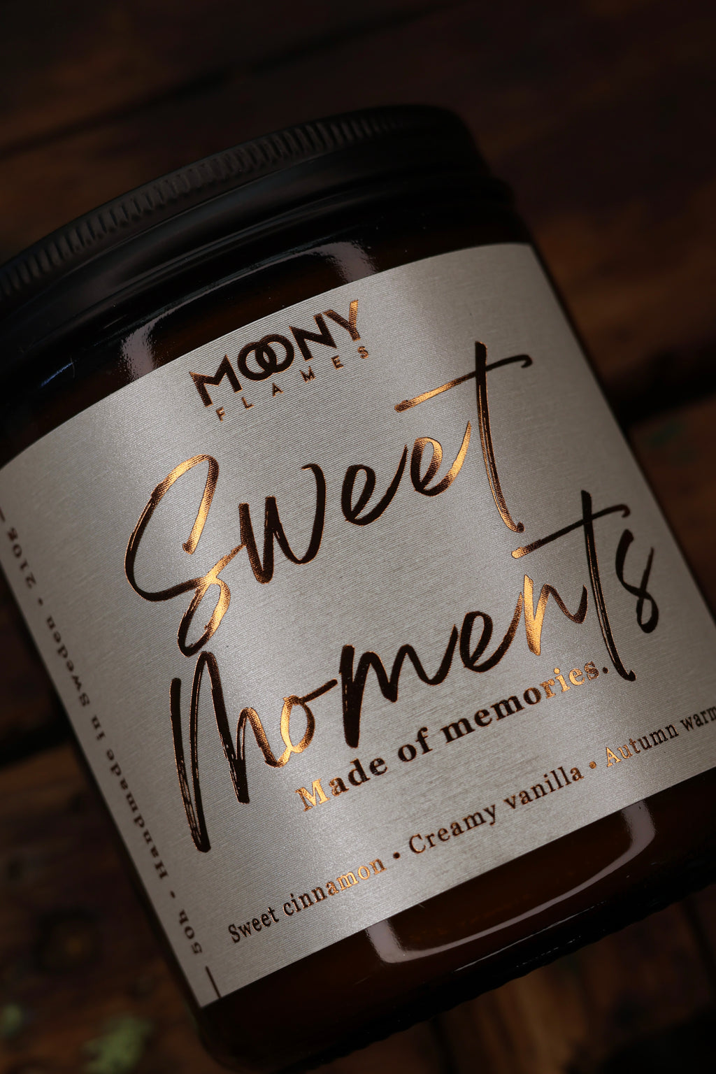 Närbild på Sweet Moments handgjorda doftljus från Moony Flames med exklusiv etikett, kopparfolie och brunt glas, tillverkat av svenskt sojavax.