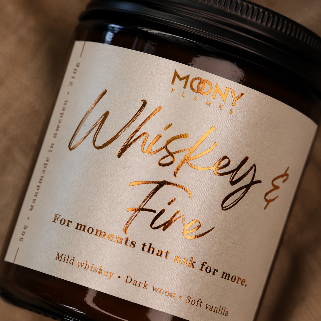 Makrobild av Whiskey & Fire doftljus från Moony Flames med exklusiv kopparfolierad etikett på amberglas. Handgjort doftljus med noter av mild whiskey, mörkt trä och mjuk vanilj, tillverkat i Småland, Sverige av växtbaserat vax.