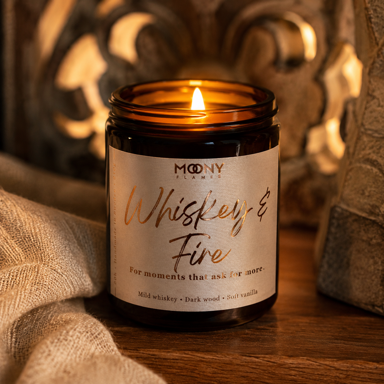 Whiskey & Fire doftljus från Moony Flames tänt i en varm och stämningsfull miljö med whiskeyglas, mörkt trä och mjuk belysning. Handgjort doftljus med noter av mild whiskey, mörkt trä och vanilj, tillverkat i Småland, Sverige.